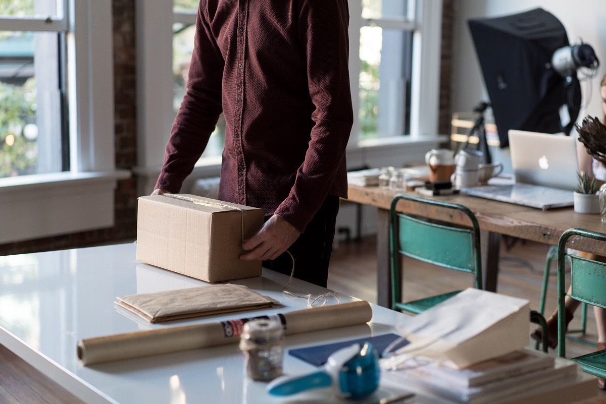 Das Foto zeigt eine männliche Person, die ein Paket für den Versand vorbereitet.