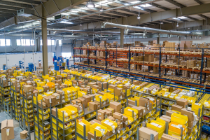 Das Bild zeigt einen großen Lagerraum mit einer Mege Kartons und gelben Boxen