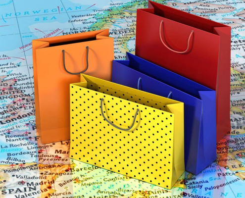 Einkaufstüten in verschiedenen Farben auf einer Europakarte symbolisieren internationalen B2B-Handel über Amazon.